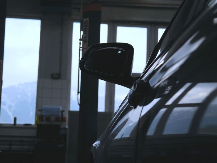 Ein Auto auf der Hebebühne in unserer Werkstatt, durch die Fenster sieht man die Berge